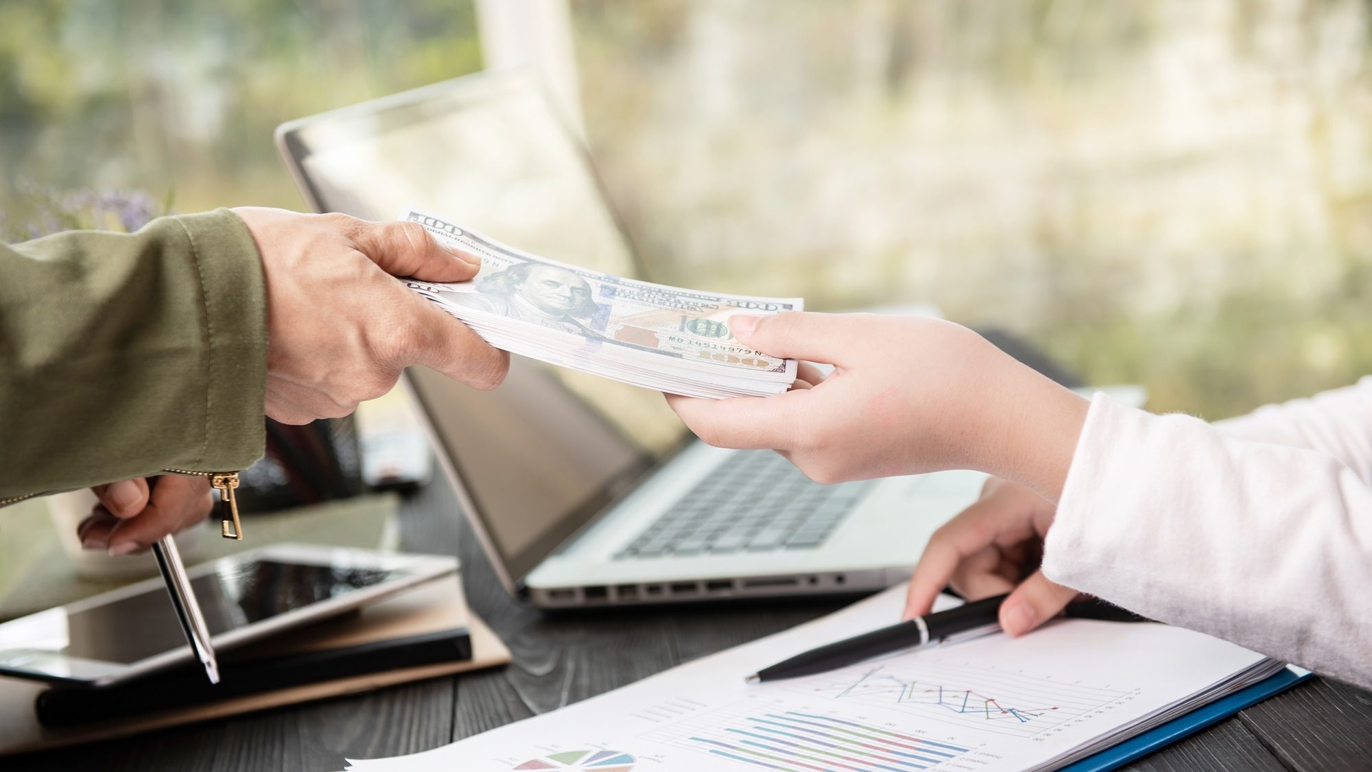 businessman giving money his partner while making contract e1721636060245